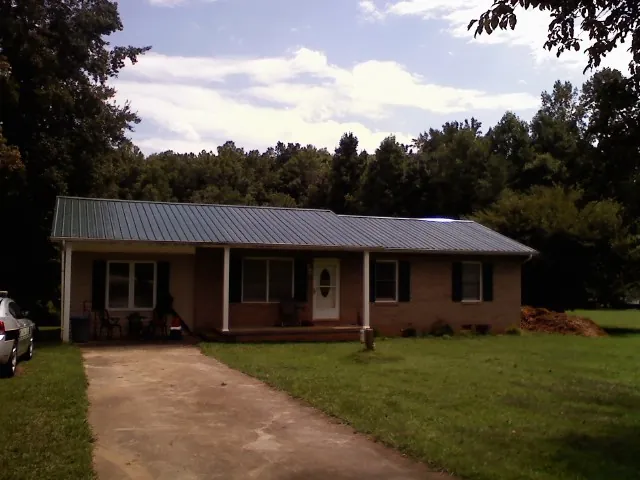 Dark green metal roof on a brick ranch with a covered porch in Huntsville